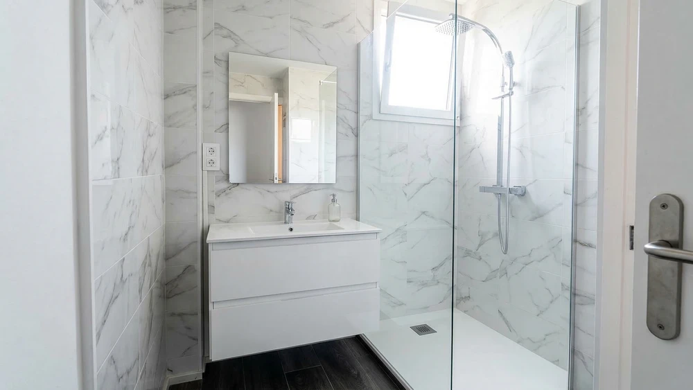 Intérieur de la salle de bains moderne avec murs gris, sol en carrelage, fenêtres avec vue sur la montagne et baignoire en pierre